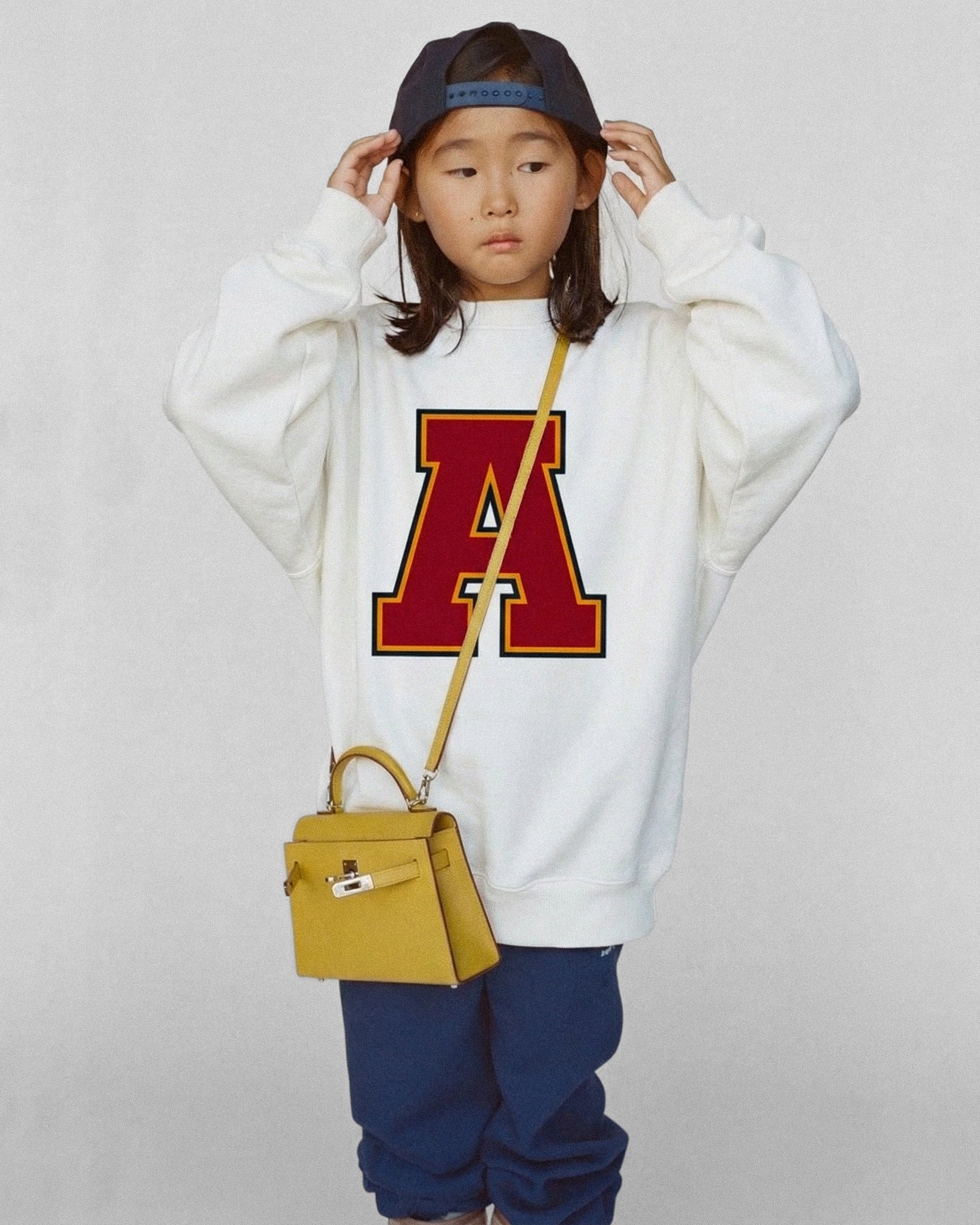 Child wearing a Baron & Buck kids varsity monogram sweatshirt in white, reflecting classic collegiate style made to match across generations.