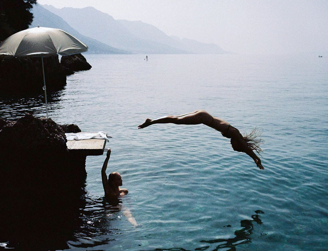 Person diving into a lake with mountains in the background