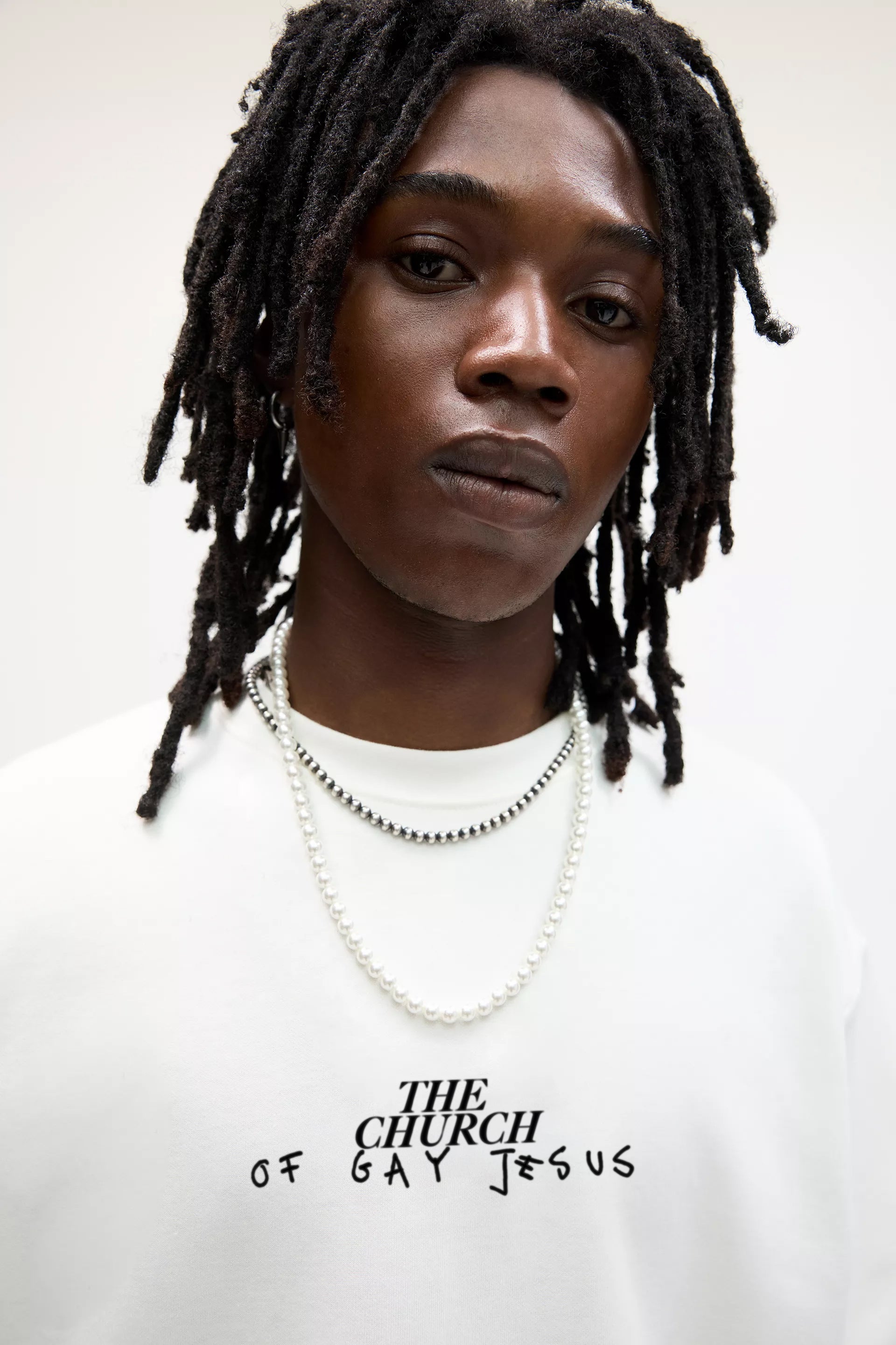 Close-up portrait featuring Baron & Buck “The Church of Gay Jesus” sweatshirt in white — expressive streetwear blending faith, art, and identity through bold typography.