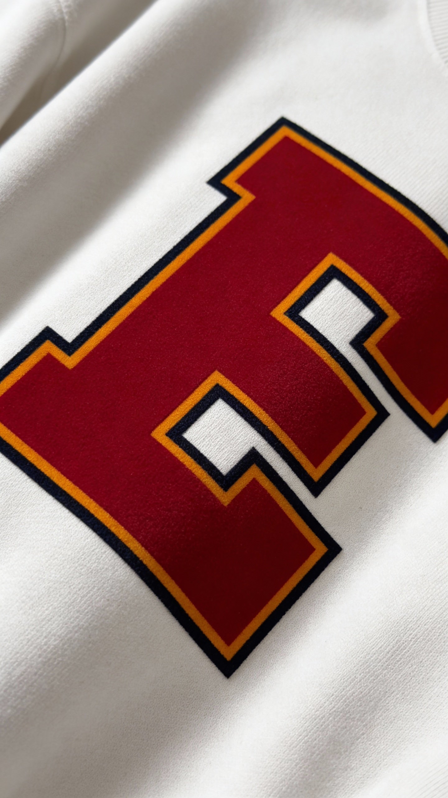 Close-up of varsity monogram letter E print on White cotton sweatshirt