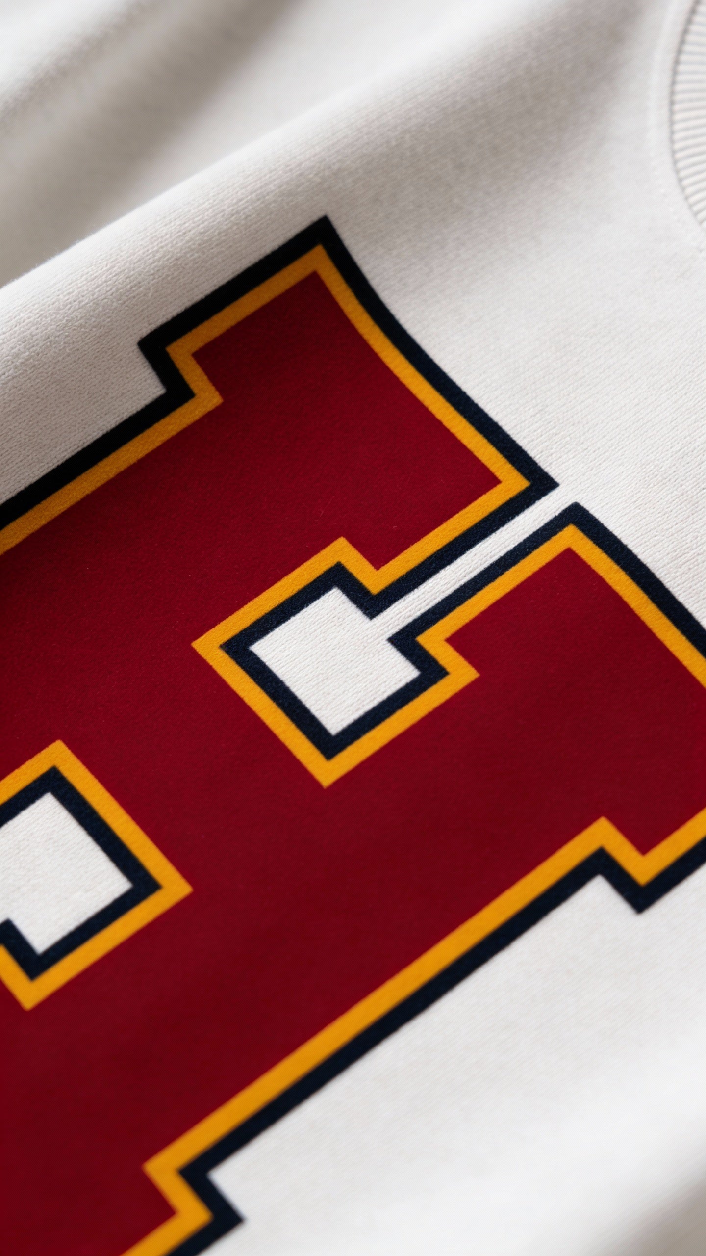 Close-up of varsity monogram letter H print on White cotton sweatshirt