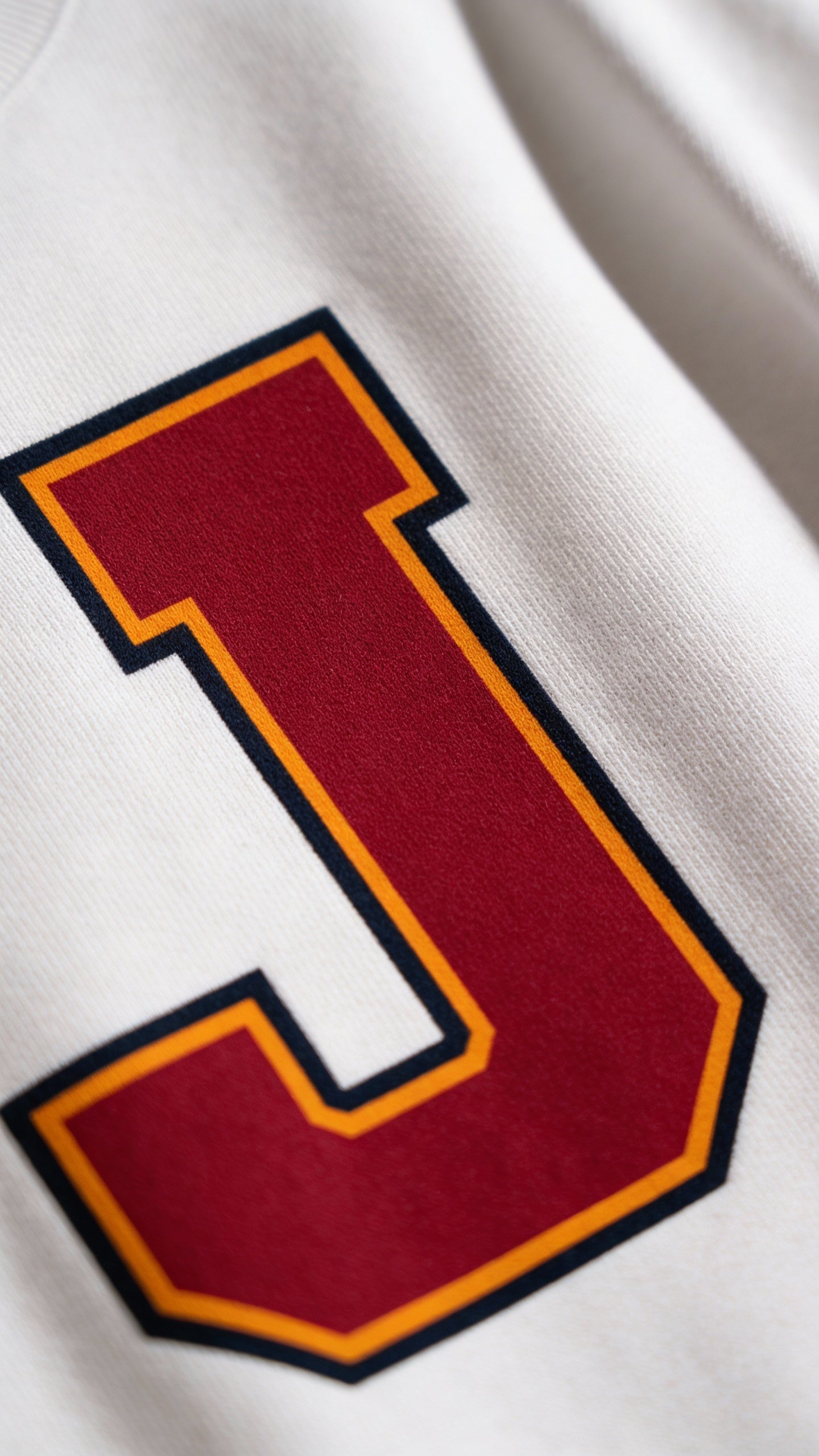 Close-up of varsity monogram letter J print on White cotton sweatshirt