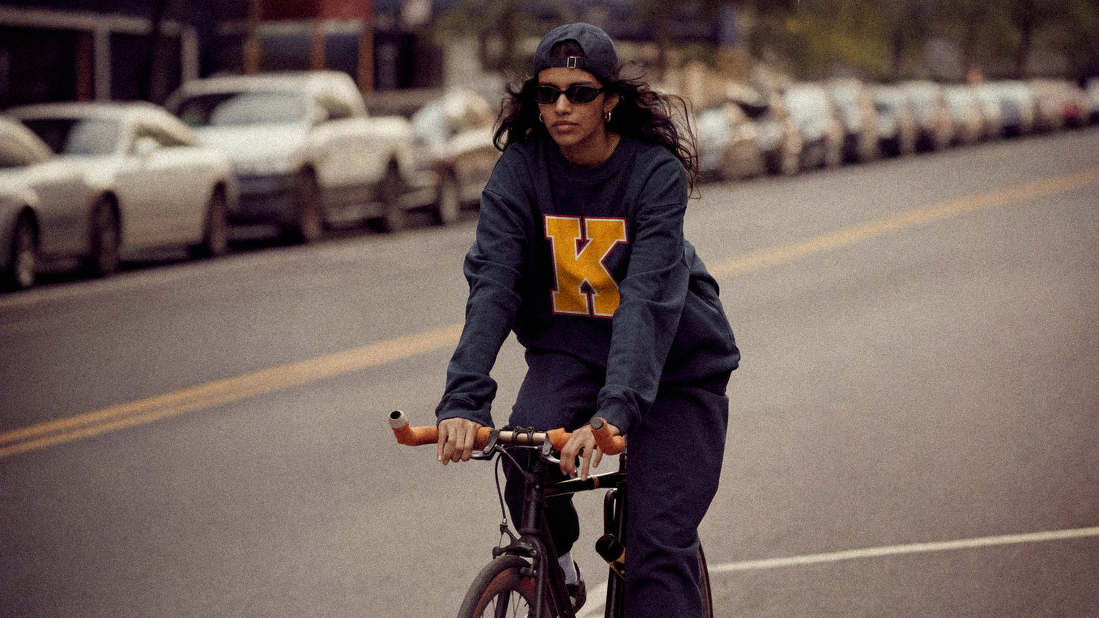 Woman wearing Baron & Buck varsity monogram K sweatshirt, unisex relaxed fit premium streetwear