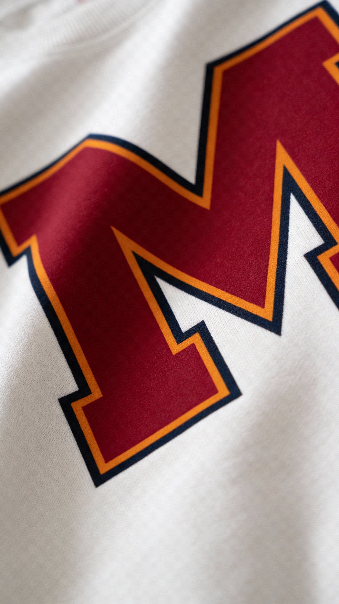 Close-up of varsity monogram letter M print on White cotton sweatshirt