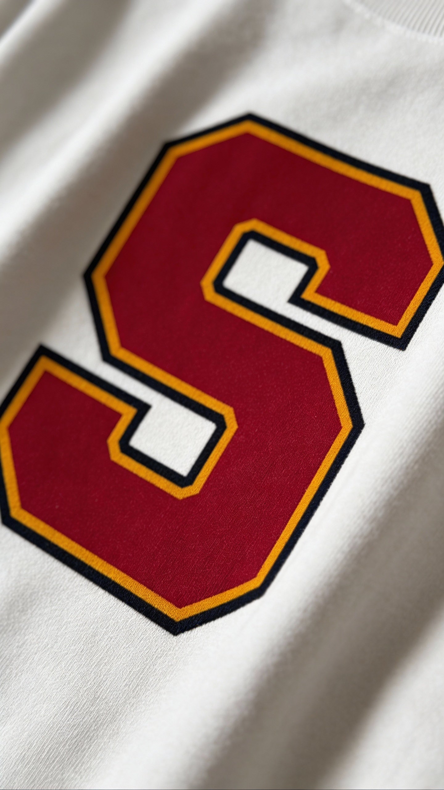 Close-up of varsity monogram letter S print on White cotton sweatshirt
