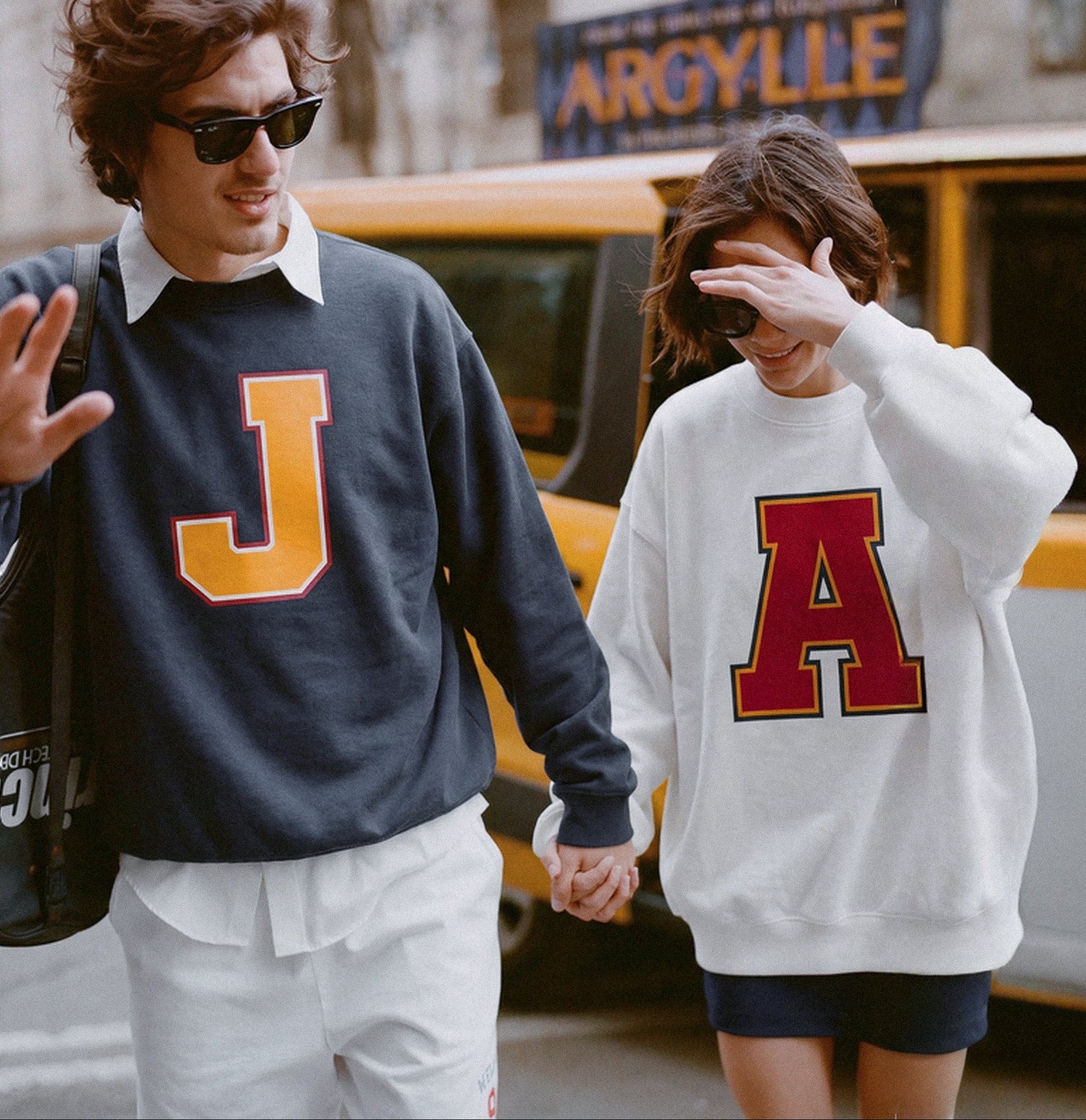 Man and woman wearing Baron & Buck varsity monogram sweatshirts with letters J and A, unisex premium streetwear